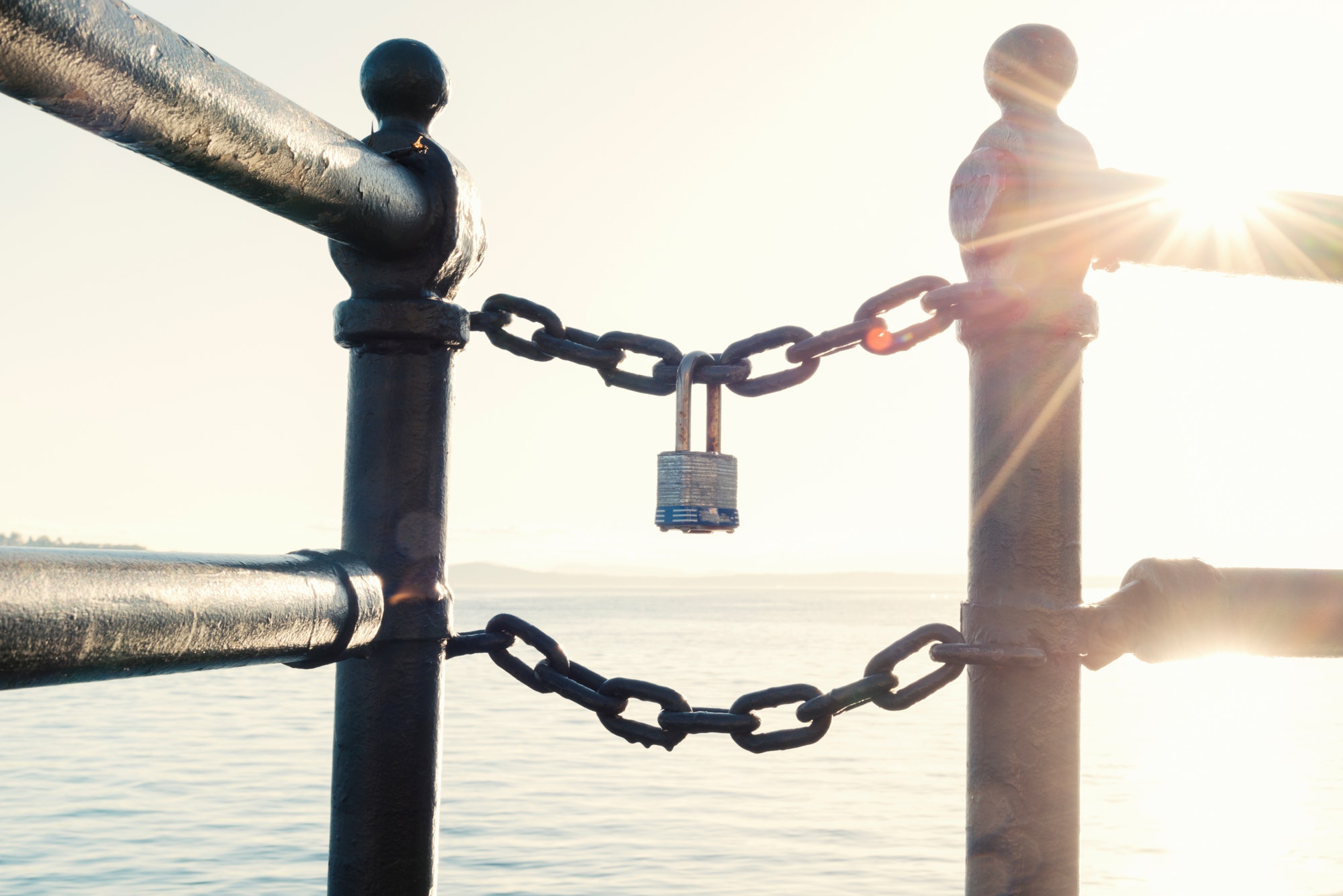 Block chain technology, a lock on a chain at sunset with sunburst.